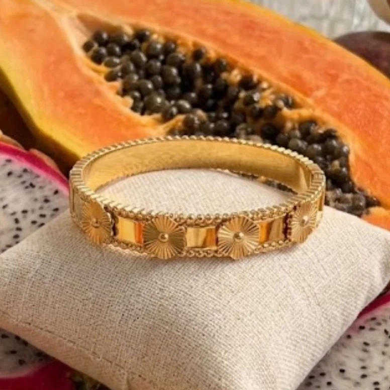 Détail des médaillons floraux ciselés et des bords perlés du bracelet Lila